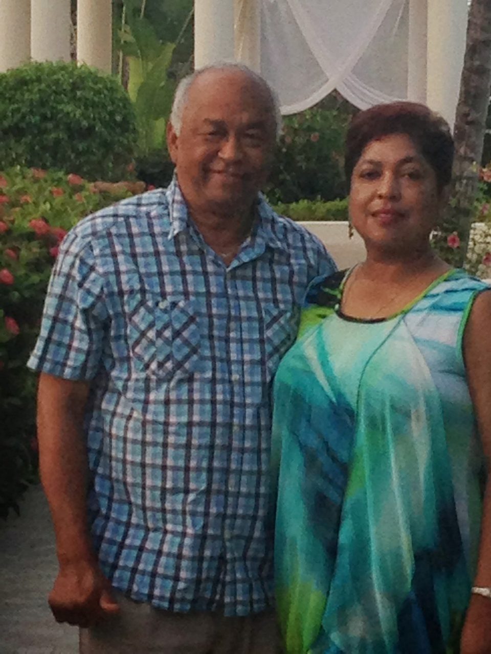 Gabriel and Shanti standing together smiling at a garden gazebo